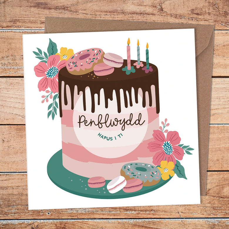 Birthday card featuring a birthday cake design and the words 'happy birthday to you' in Welsh- Pen-blwydd hapus i ti