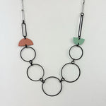 Handmade statement necklace by Deryn featuring black rings and coloured semi circles.