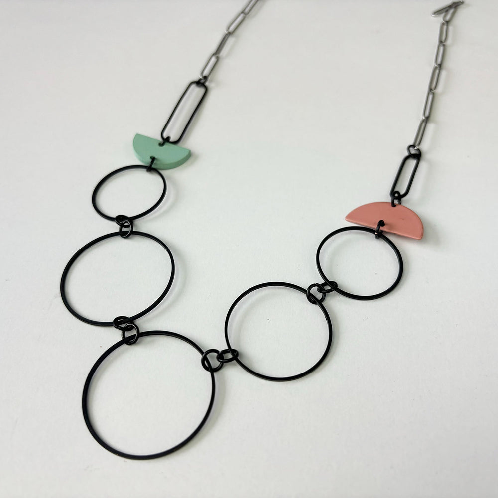 Handmade statement necklace by Deryn featuring black rings and coloured semi circles.