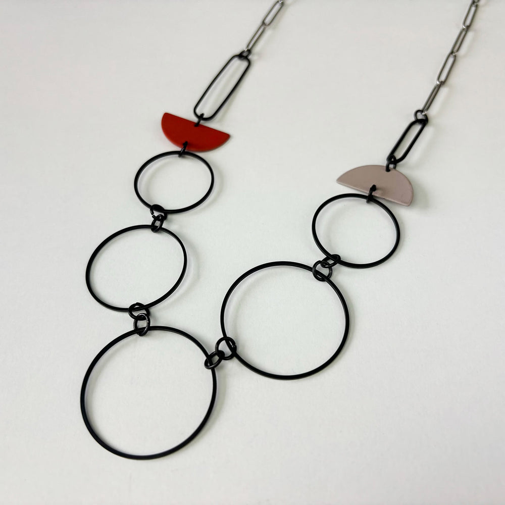 Handmade statement necklace by Deryn featuring black rings and coloured semi circles.