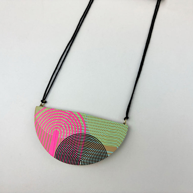 Handmade large semi circle pendant made from double sided reclaimed leather in a geometric arches pattern on black cord