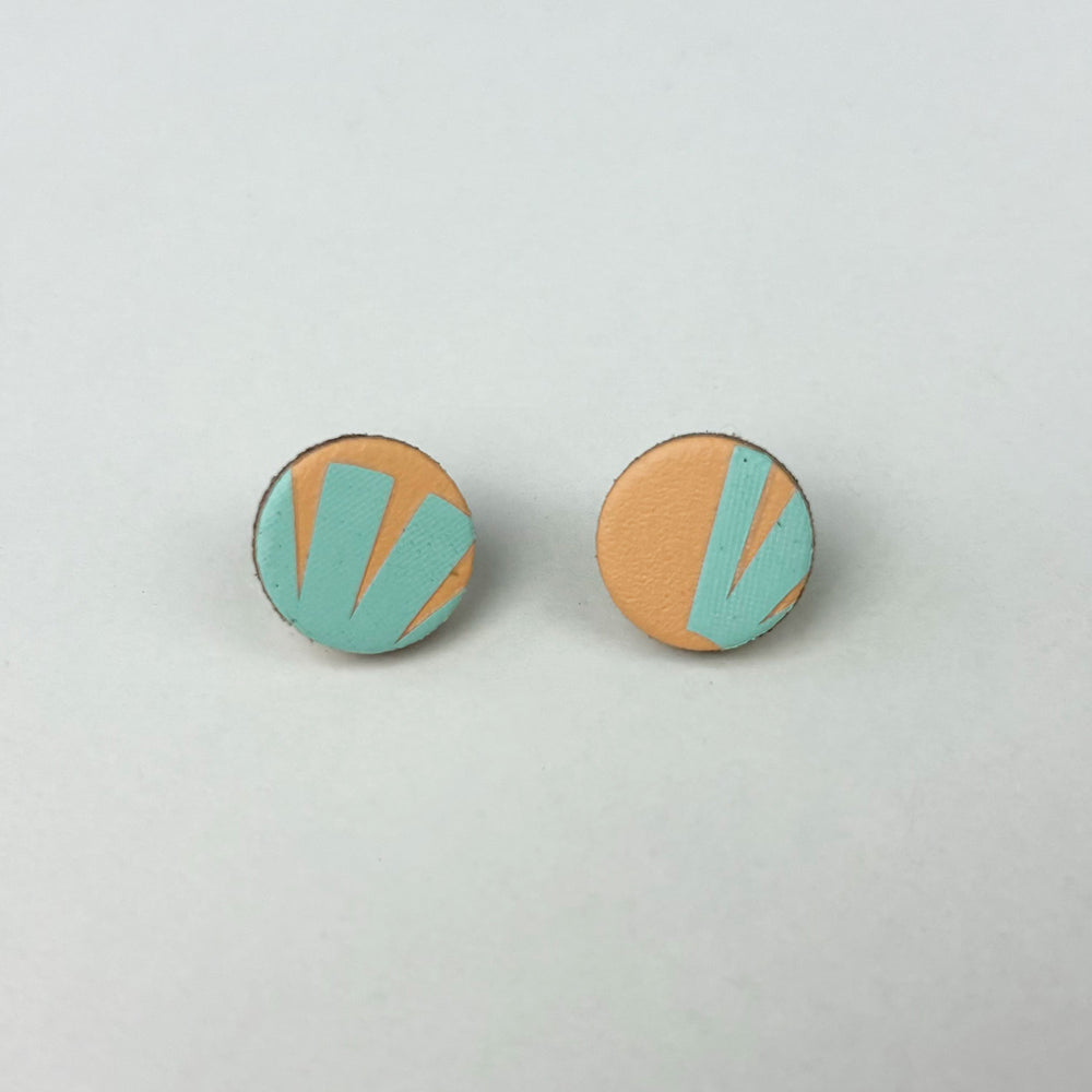 Handmade stud earrings made from reclaimed leather circles in peach and pale blue with a geometric pattern