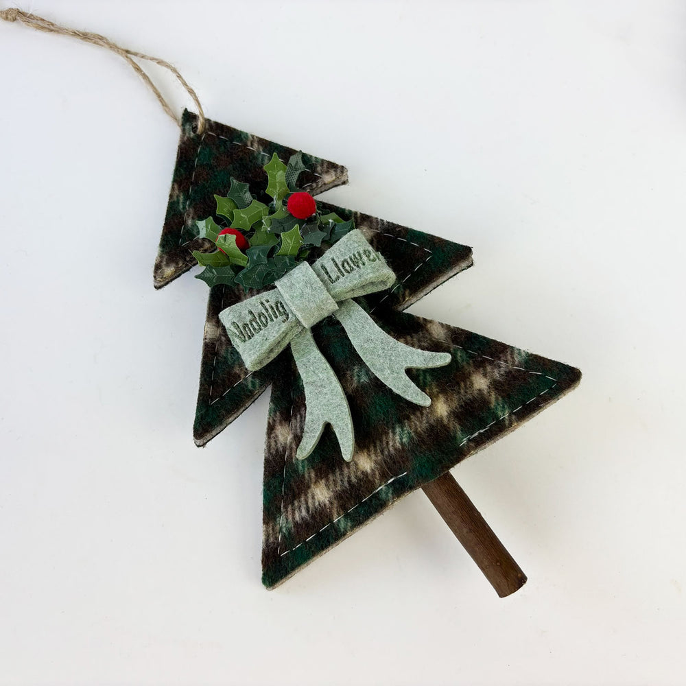 Decorative Christmas tree ornament with holly and ribbon on a white background and the wrods 'Nadolig Llawen
