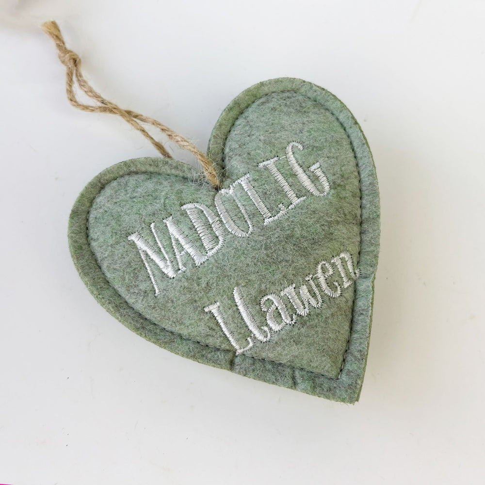 Heart-shaped green ornament with embroidered text on a white background