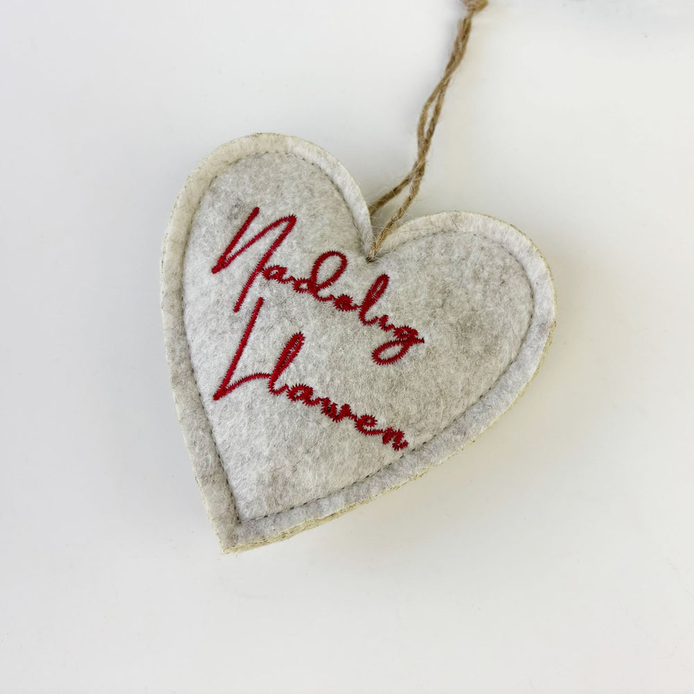 Heart-shaped hanging ornament with embroidered text on a white background
