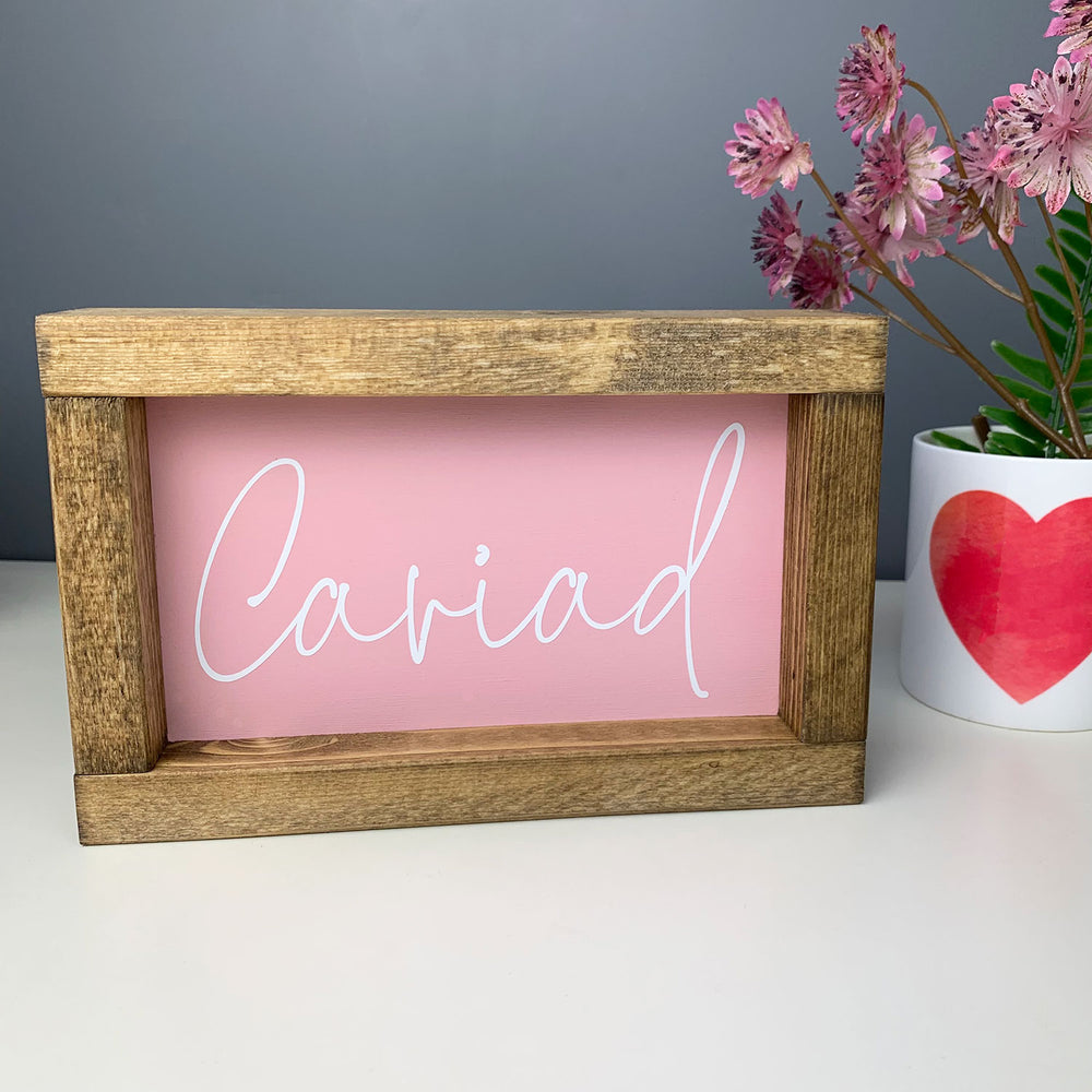 Welsh art of the word 'love' written in Welsh and framed in a wooden border